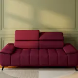 Un canapé rouge profond, avec un mur vert sauge derrière. Une table d'appoint en bois avec un vase noir et des herbes séchées. Quelle couleur associer avec un canapé rouge ?