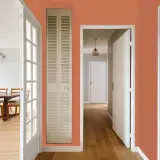 Couleur tendance 2026 : un couloir chaleureux avec des portes ouvertes sur une salle à manger et un passage.