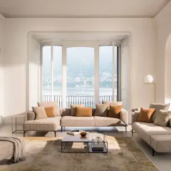Un salon cocooning avec un canapé d'angle beige, des coussins douillets et une vue imprenable sur un lac.