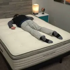 Un homme s'allonge sur le dos sur un matelas Avocado, idéal pour ceux qui aiment dormir sur le ventre.