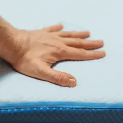 Main posée sur un matelas en mousse, testant son sens de confort et de soutien.