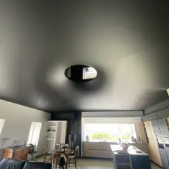 Plafond noir tendu, un cache-misère habile pour un plafond abîmé, avec une ouverture circulaire laissant apercevoir le ciel.
