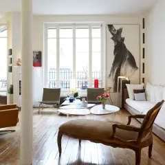 Salon lumineux avec des styles de meubles anciens, dont une méridienne en bois sculpté et des fauteuils en cuir.