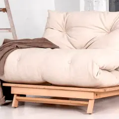 Un canapé futon beige avec une couverture marron drapée. Idéal pour savoir comment rendre un canapé plus confortable.