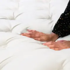 Les mains caressent un matelas blanc, explorant sa douceur. Un matelas zone de confort pour des nuits paisibles.