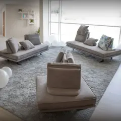 Salon moderne avec un canapé designer connu, des coussins moelleux et des ballons blancs sur un tapis épais.