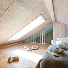 Chambre mansardée avec plafond texturé pour une excellente isolation phonique. Jouets sur le parquet, lit douillet.