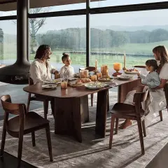 Une famille partage un repas autour d'une table à manger en bois. La hauteur de la table est parfaite pour la vue panoramique sur la campagne.