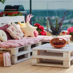 Un canapé en palette plan, confortable et coloré, orne cette terrasse avec des coussins douillets et des fleurs vives.