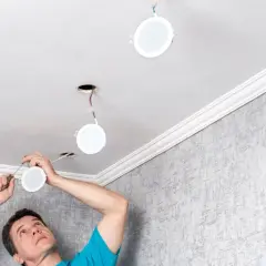 Installation d'un spot LED 220V sans transformateur. Un homme installe des luminaires ronds au plafond.