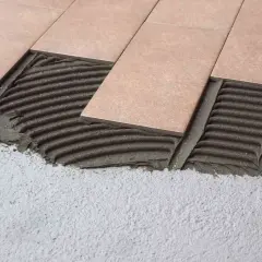 Pose de carrelage rectangulaire sur mortier frais. Les carreaux sont posés sur une couche de colle texturée, prêts à être ajustés.