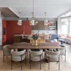 Un espace de vie salle à manger moderne avec une table en bois, des chaises confortables et une cuisine aux armoires rouges vives.
