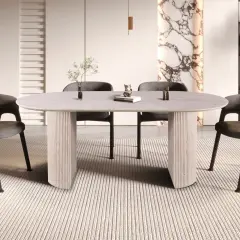 Table ovale moderne pour 8 personnes, aux dimensions généreuses, avec pieds sculpturaux et chaises grises confortables.