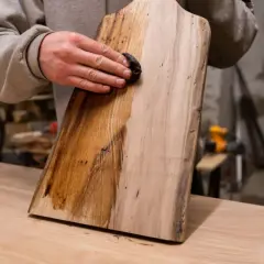 Application d'une solution pour le vieillir du bois, peut-être du bicarbonate de soude, sur une planche. La moitié gauche est foncée, l'autre est claire.