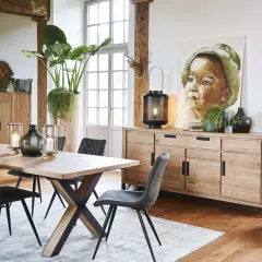 Une salle à manger avec une table en bois, des chaises grises et un buffet en chêne. Une belle idée déco salle à manger industrielle avec un tableau et des plantes.