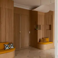 Élégante déco entrée maison en bois, avec banquettes confortables et coussins graphiques.