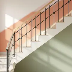 Escalier moderne avec rampe en bois et barreaux noirs. Les murs sont peints en deux tons : pêche et vert sauge, une couleur escalier tendance.