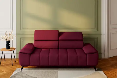 Un canapé rouge profond, avec un mur vert sauge derrière. Une table d'appoint en bois avec un vase noir et des herbes séchées. Quelle couleur associer avec un canapé rouge ?