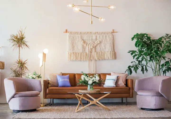Salon moderne avec canapé en cuir marron, fauteuils roses poudrés et table basse en bois clair. Quelle couleur avec bois clair ? Le rose poudré et le marron s'harmonisent parfaitement.
