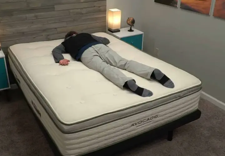 Un homme s'allonge sur le dos sur un matelas Avocado, idéal pour ceux qui aiment dormir sur le ventre.