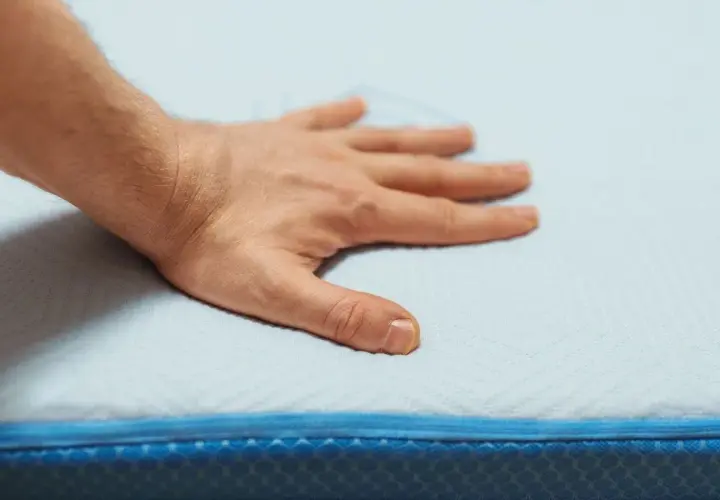 Main posée sur un matelas en mousse, testant son sens de confort et de soutien.
