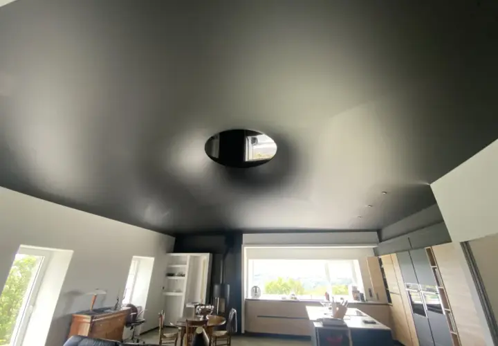Plafond noir tendu, un cache-misère habile pour un plafond abîmé, avec une ouverture circulaire laissant apercevoir le ciel.