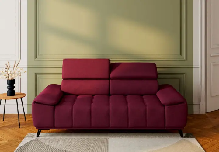 Un canapé rouge profond, avec un mur vert sauge derrière. Une table d'appoint en bois avec un vase noir et des herbes séchées. Quelle couleur associer avec un canapé rouge ?