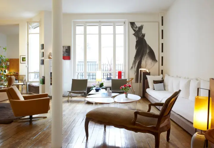 Salon lumineux avec des styles de meubles anciens, dont une méridienne en bois sculpté et des fauteuils en cuir.