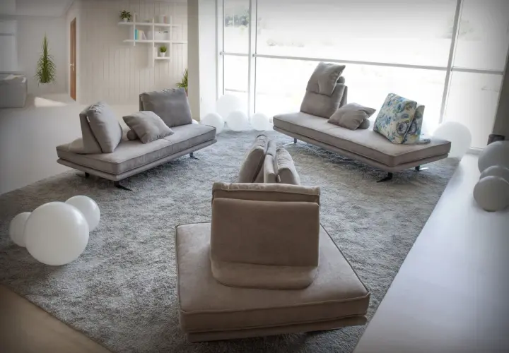 Salon moderne avec un canapé designer connu, des coussins moelleux et des ballons blancs sur un tapis épais.
