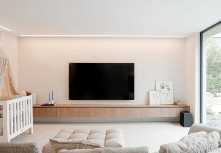 Un meuble TV suspendu, épuré et en bois, avec une télévision et des décorations. Idéal pour un salon moderne.