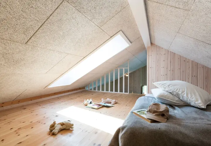 Chambre mansardée avec plafond texturé pour une excellente isolation phonique. Jouets sur le parquet, lit douillet.