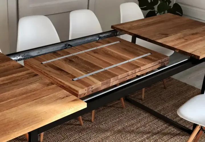 Détail du système de rallonge de table en bois, montrant les coulisses métalliques et les extensions empilées.