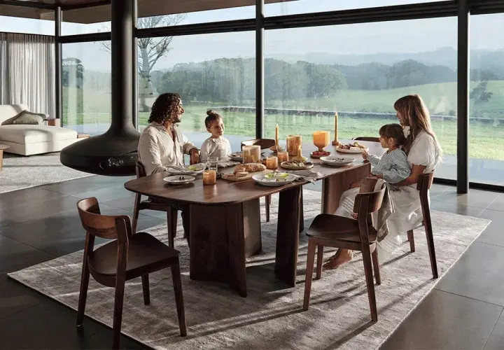 Une famille partage un repas autour d'une table à manger en bois. La hauteur de la table est parfaite pour la vue panoramique sur la campagne.