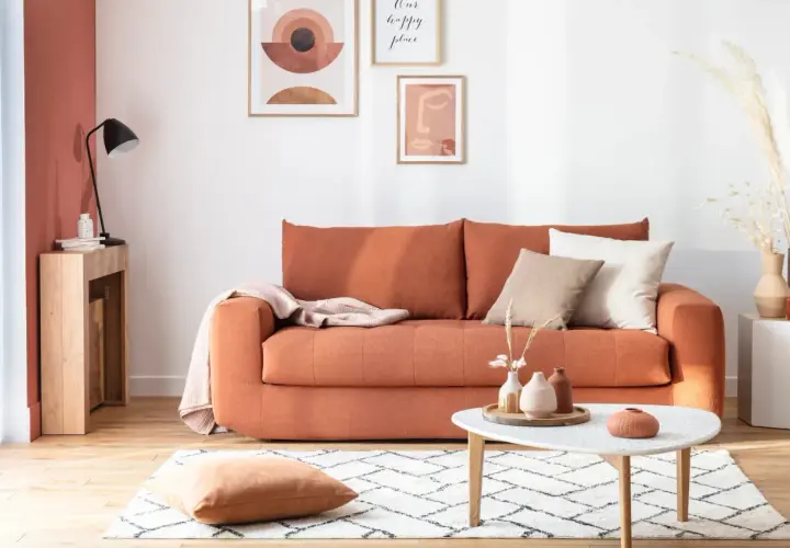 Canapé convertible orange, prêt à changer sommier. Déco bohème avec coussins, plaid et art mural.