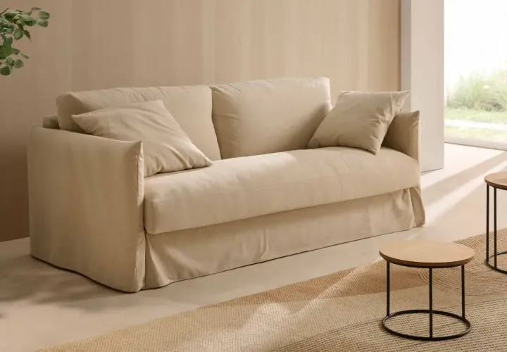 Un canapé beige confortable, des coussins douillets, une plante verte et des tables basses en bois. Quelle déco avec canapé beige pour un salon cosy et lumineux.
