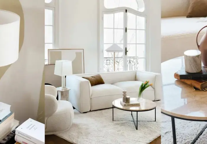 Un salon sans meuble TV, avec un canapé blanc, des lampes, des livres et une table basse en marbre.