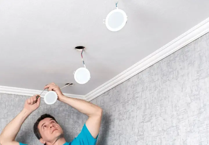 Installation d'un spot LED 220V sans transformateur. Un homme installe des luminaires ronds au plafond.