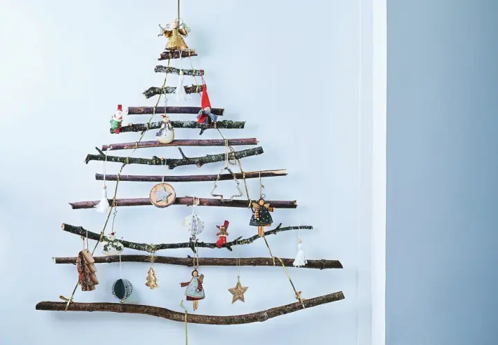 Arbre de Noël original à fabriquer soi-même avec des branches de récupération. Décoré de petites figurines et ornements suspendus.