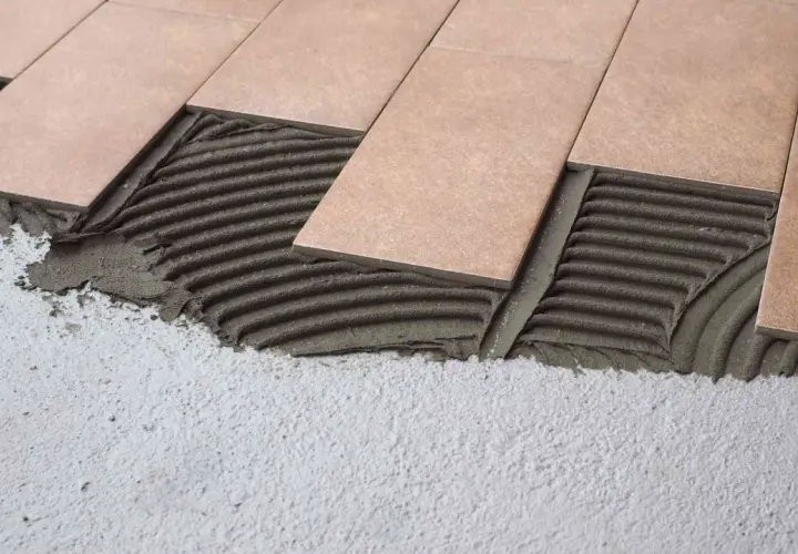 Pose de carrelage rectangulaire sur mortier frais. Les carreaux sont posés sur une couche de colle texturée, prêts à être ajustés.