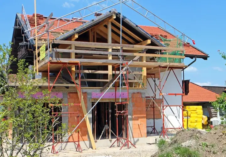 Une maison en pleine rénovation, avec échafaudages et matériaux de construction. Les propriétaires sont occupés à faire des travaux dans leur maison.