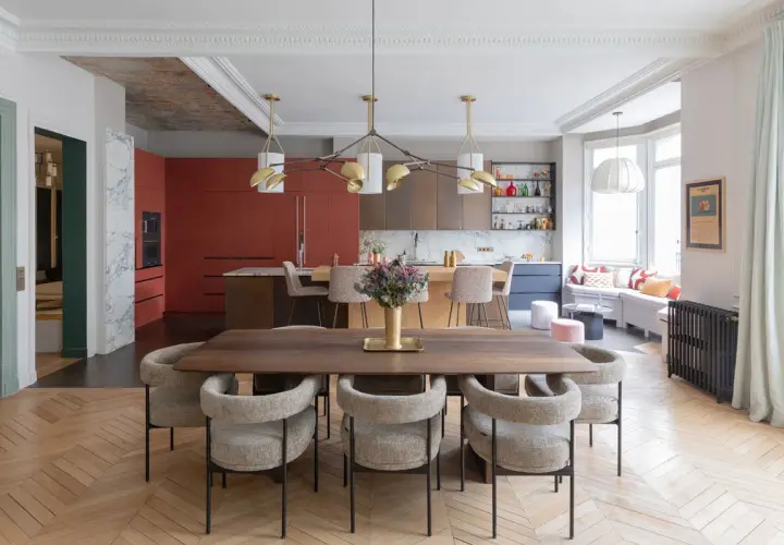 Un espace de vie salle à manger moderne avec une table en bois, des chaises confortables et une cuisine aux armoires rouges vives.