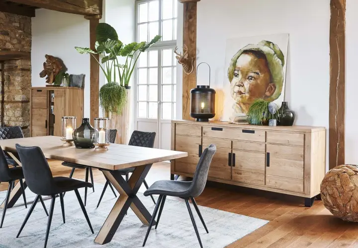 Une salle à manger avec une table en bois, des chaises grises et un buffet en chêne. Une belle idée déco salle à manger industrielle avec un tableau et des plantes.