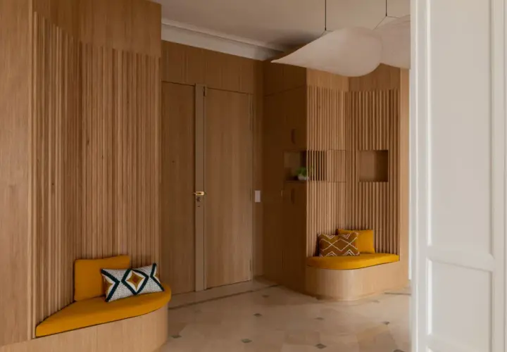 Élégante déco entrée maison en bois, avec banquettes confortables et coussins graphiques.