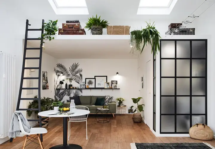 Aménagement intérieur appartement moderne avec mezzanine, échelle noire, mur végétal stylisé, mobilier design et verrière industrielle.