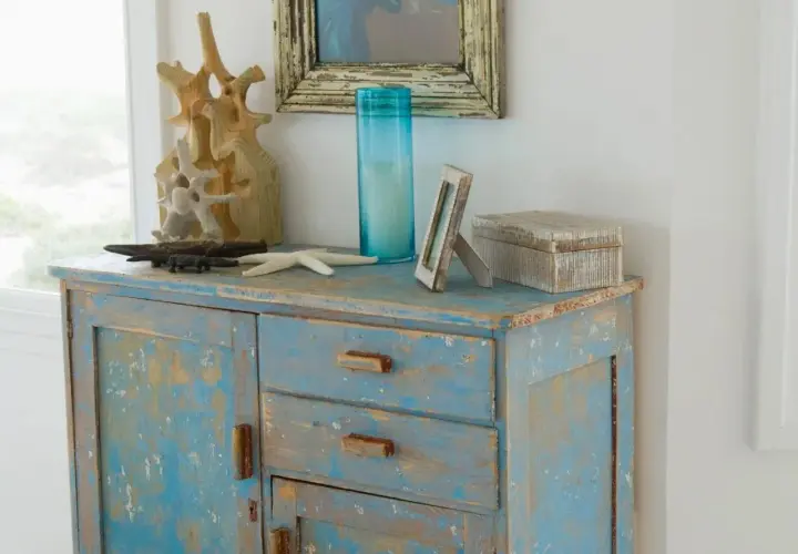 Meuble bleu délavé avec une patine bois effet vieilli, décoré d'objets marins et d'une boîte en bois.