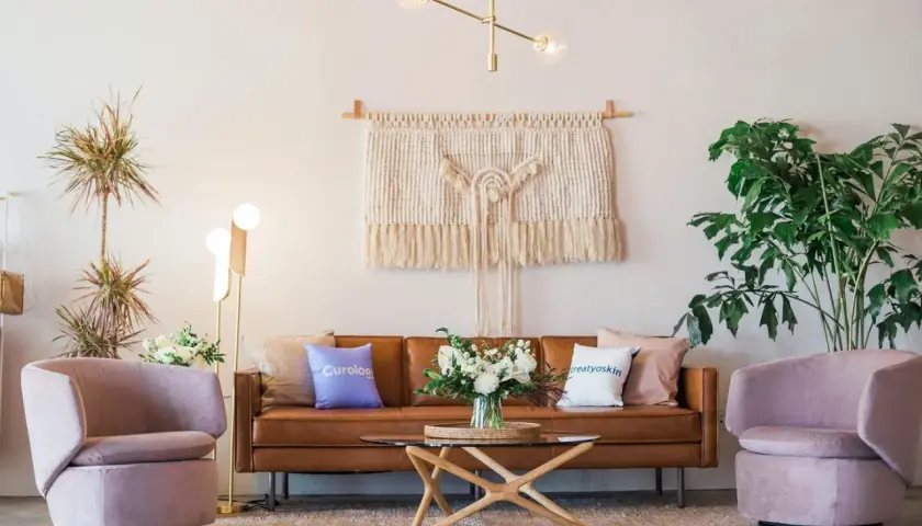Salon moderne avec canapé en cuir marron, fauteuils roses poudrés et table basse en bois clair. Quelle couleur avec bois clair ? Le rose poudré et le marron s'harmonisent parfaitement.