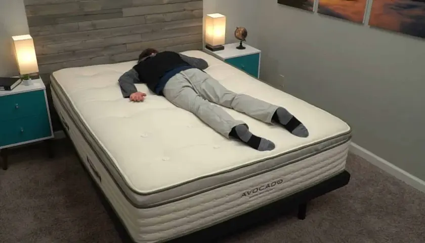 Un homme s'allonge sur le dos sur un matelas Avocado, idéal pour ceux qui aiment dormir sur le ventre.