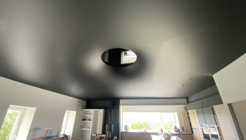 Plafond noir tendu, un cache-misère habile pour un plafond abîmé, avec une ouverture circulaire laissant apercevoir le ciel.