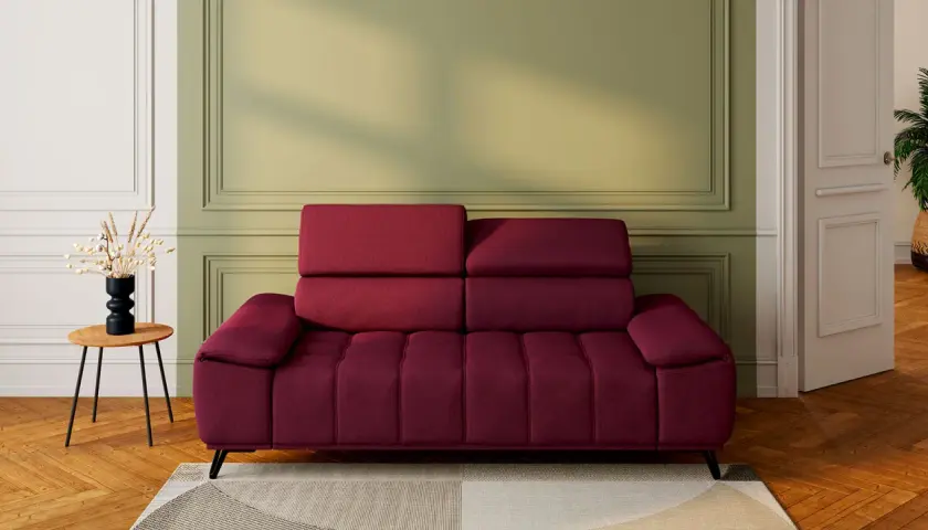 Un canapé rouge profond, avec un mur vert sauge derrière. Une table d'appoint en bois avec un vase noir et des herbes séchées. Quelle couleur associer avec un canapé rouge ?