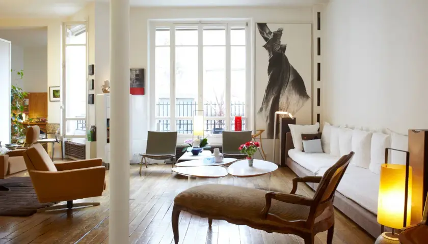 Salon lumineux avec des styles de meubles anciens, dont une méridienne en bois sculpté et des fauteuils en cuir.